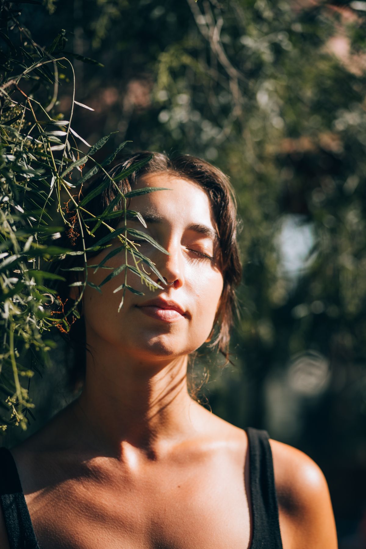 Woman meditating outdoors surrounded by greenery with eyes closed