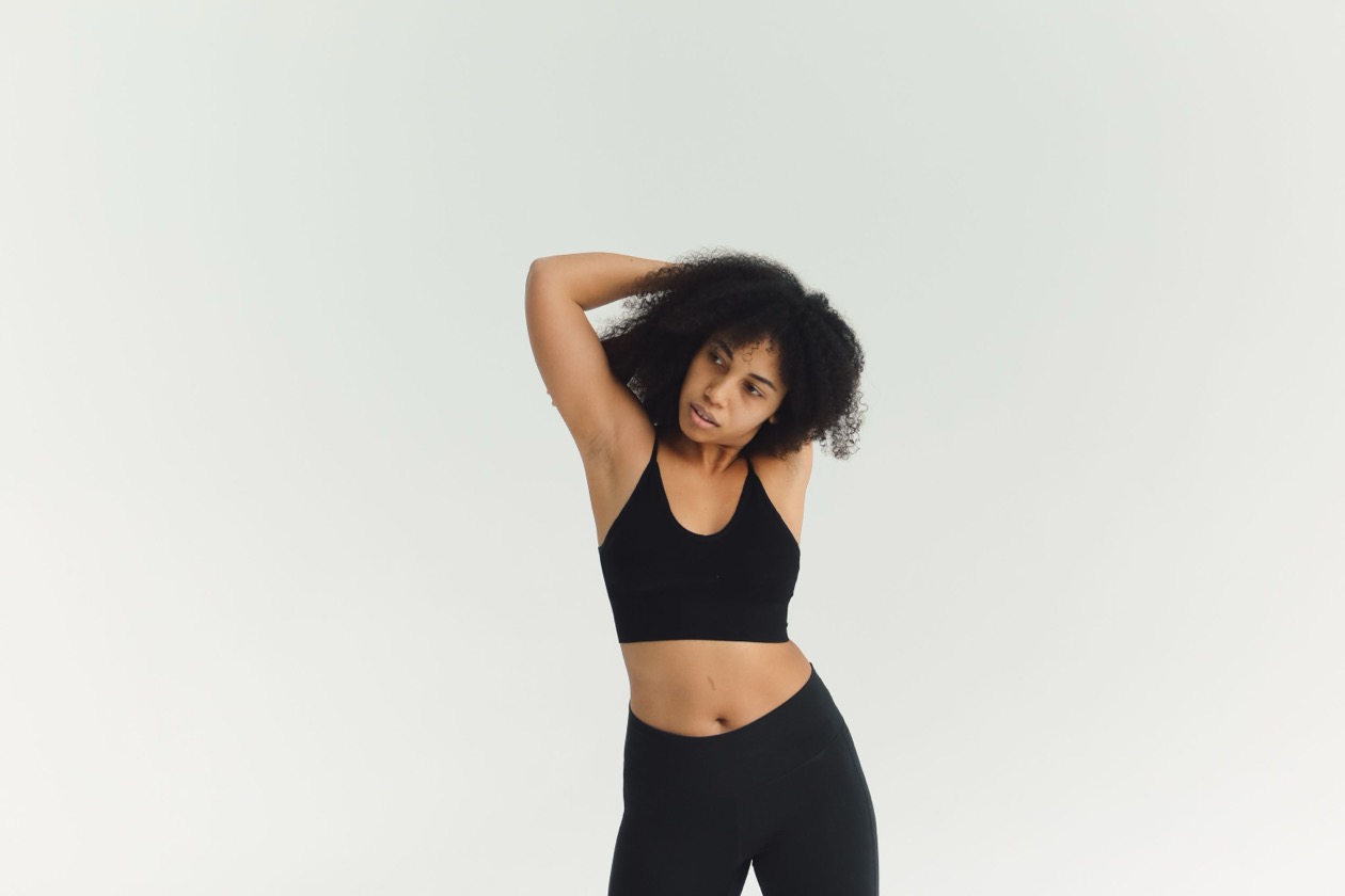 Woman stretching her shoulders in a bright studio, demonstrating the chest opener stretch