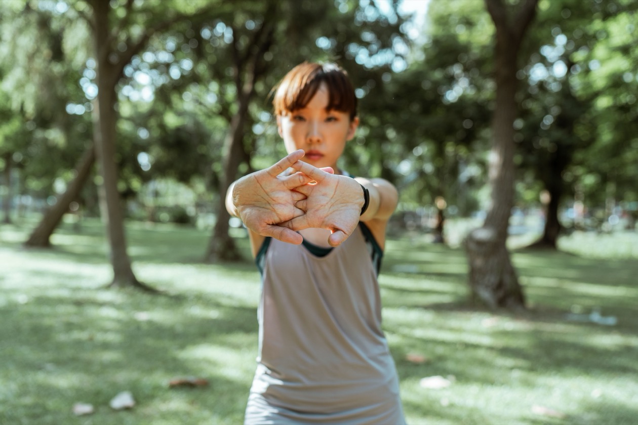 Woman doing warm up stretching exercises in a park before training